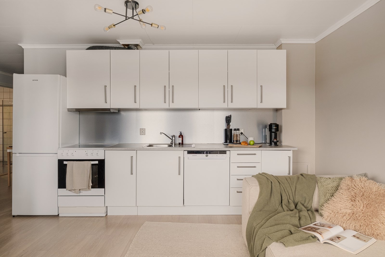 Kjøkkenet har innredning med glatte fronter og laminat benkeplate, samt frittstående hvitevarer. Galleribilde