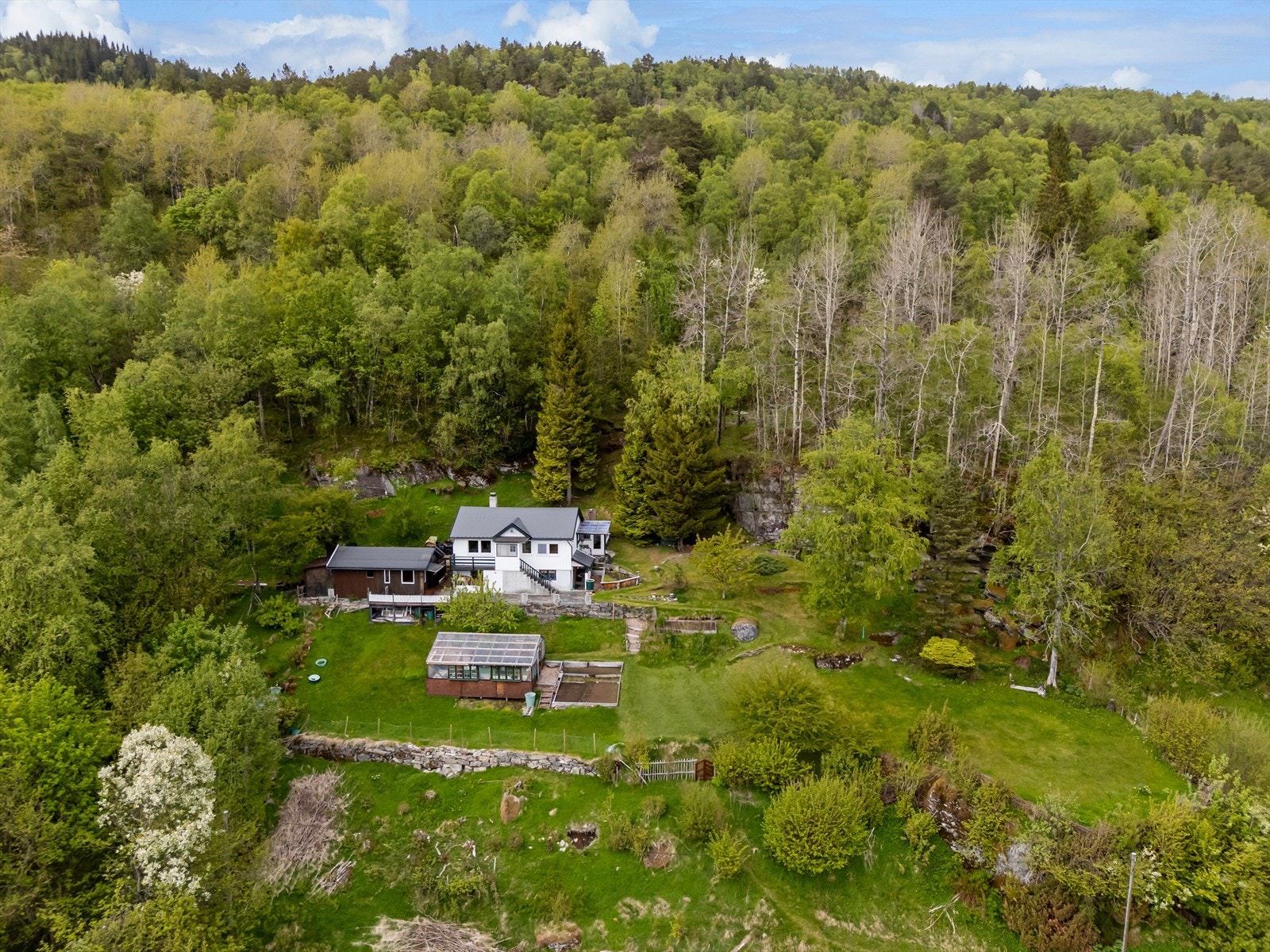 Tomten er variert og tilrettelagt med terrasserte nivåer og stier. Galleribilde