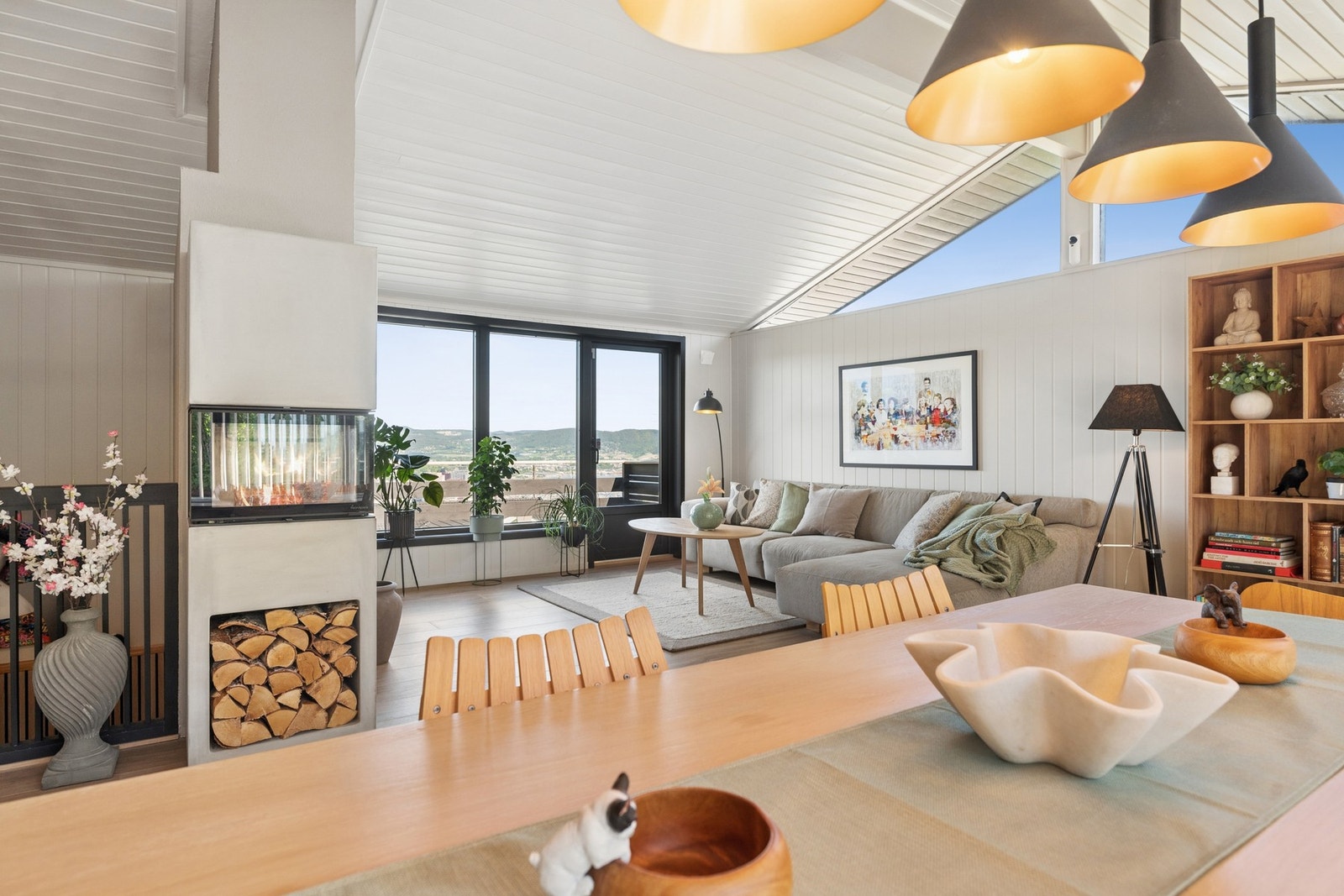 Stuen er lys med store vindusflater, peis og god plass til både sofa og spisegruppe. Galleribilde