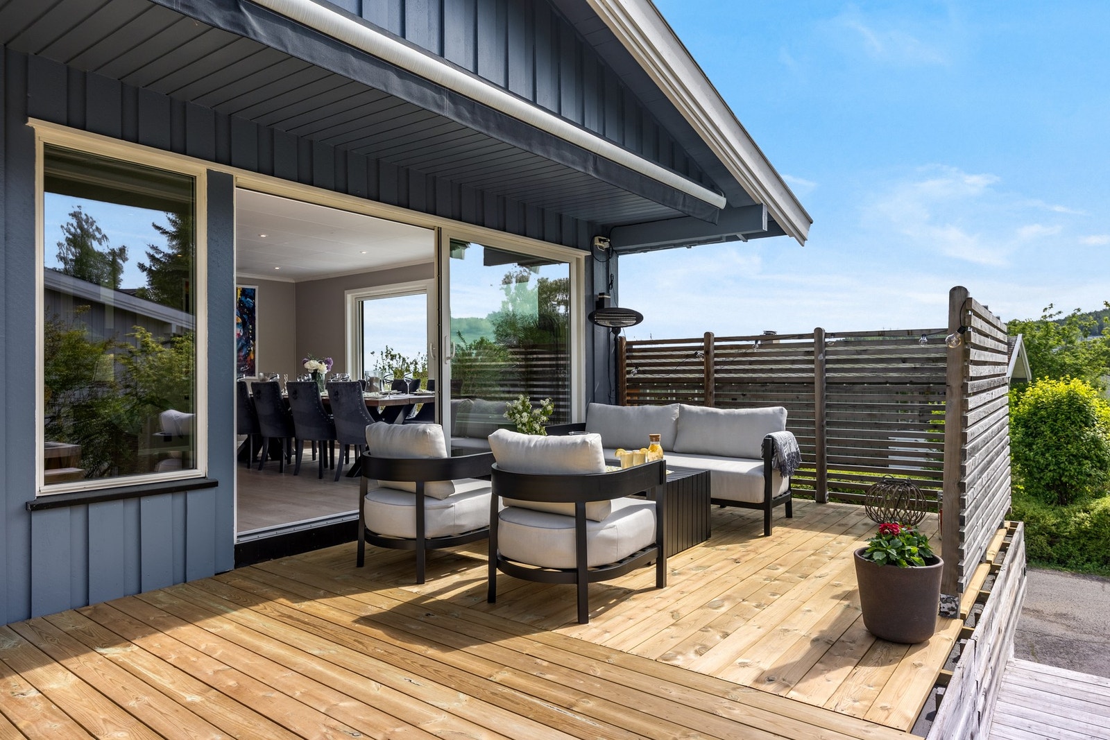 Sømløs overgang mellom inne og ute - store skyvedører åpner direkte mot en romslig og solrik terrasse med behagelig sittegruppe og utsikt mot naturen. Galleribilde