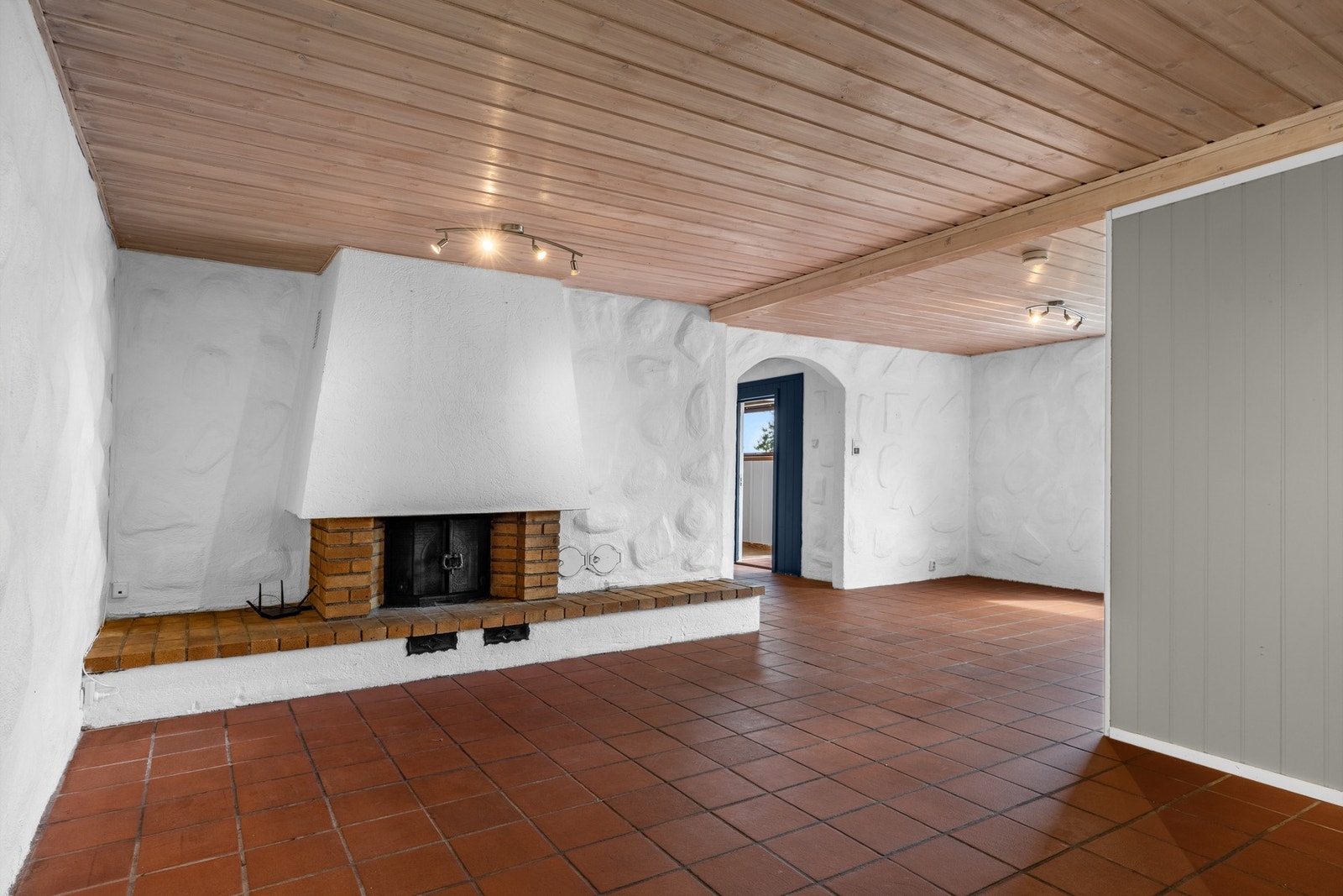 Romslig og lys kjellerstue med sjarmerende muret peis, tretak og terrakottafliser - et rom med stort potensial for hobbyrom, gjesterom eller familiekrok. Galleribilde