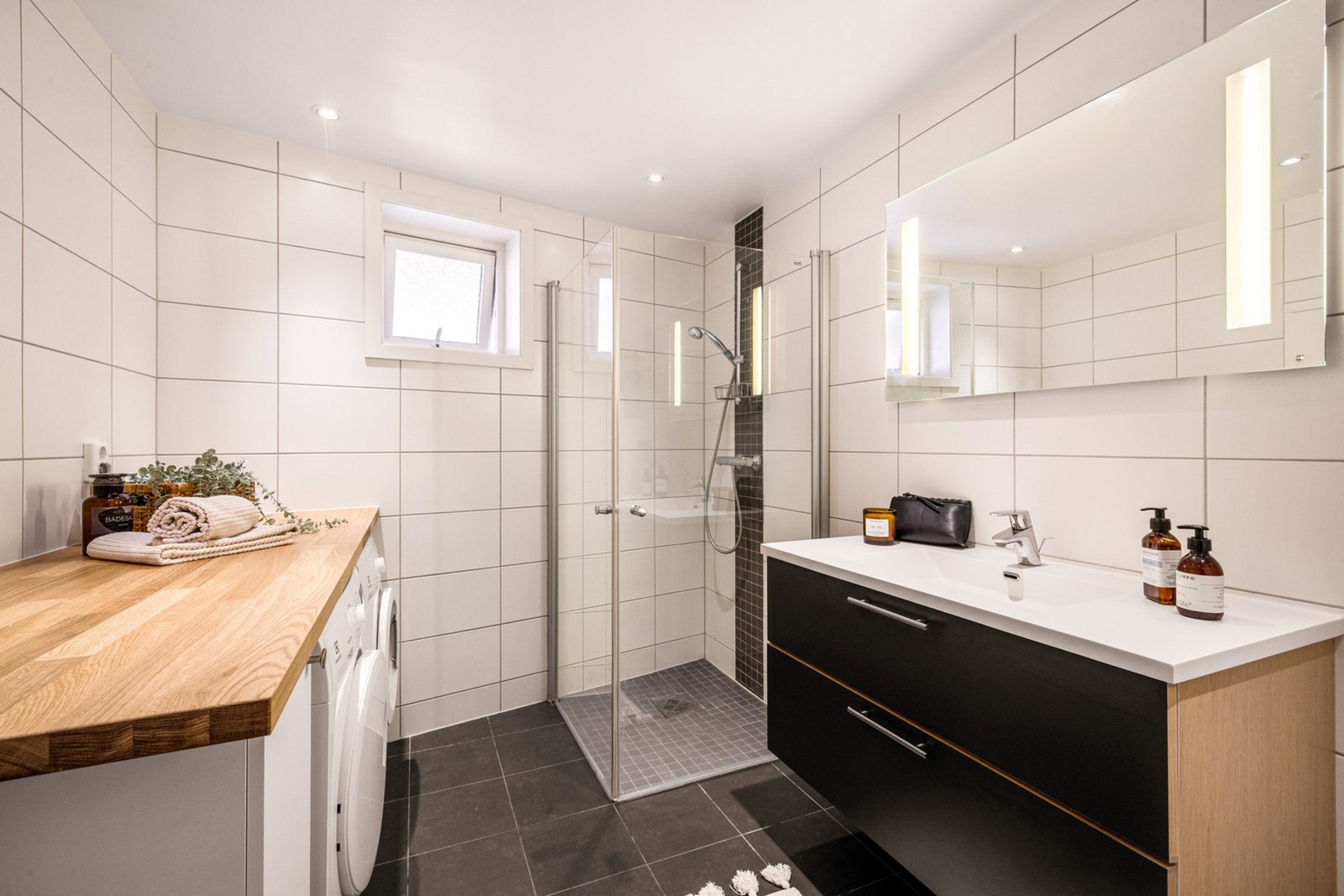 Badet inneholder møblement/speil og belysning, vegghengt toalett, innfelbart dusjhjørne i glass, dusjgarnityr, opplegg for
vaskemaskin/tørketrommel, innredning/skap og benkeplate Galleribilde