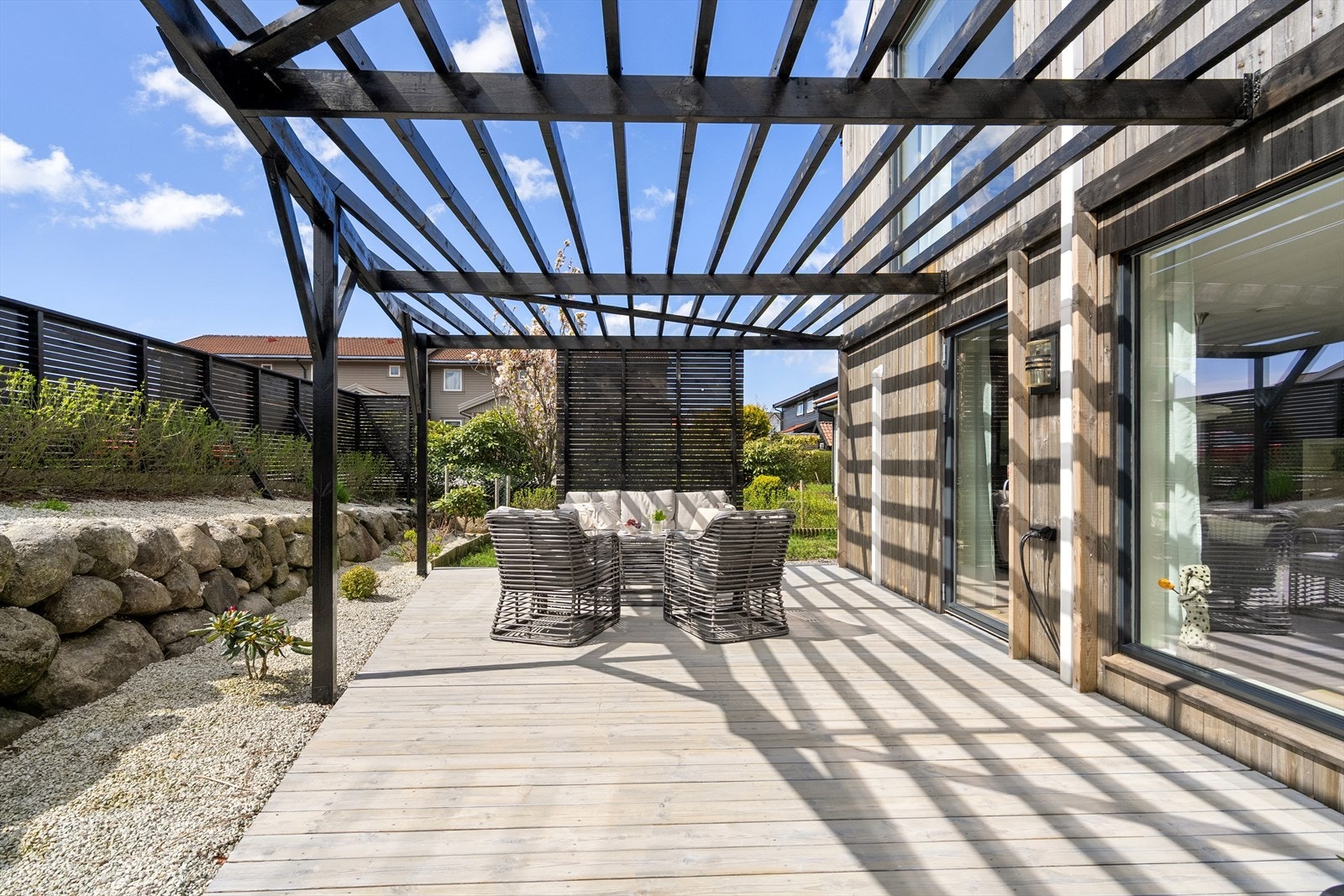 Fra stuen er det enkel tilgang til uteområdet med terrasse, levegger og pergola, hvor gode solforhold og skjermede omgivelser gir flotte rammer for både avslapning og sosiale sammenkomster. Galleribilde