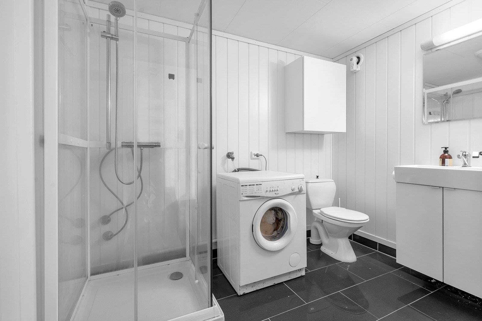 Badet har fliser på gulv og malte vegger, samt opplegg for vaskemaskin og dusjkabinett. Galleribilde