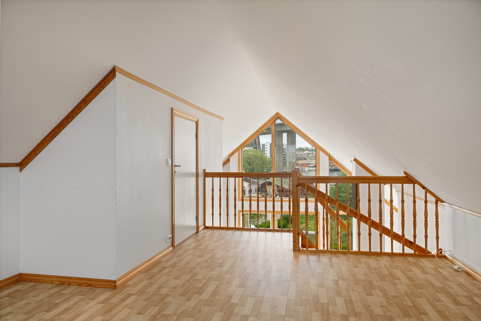 Loftstue på hemsen med utsyn ned mot stuen og ut gjennom de store vinduene. Galleribilde