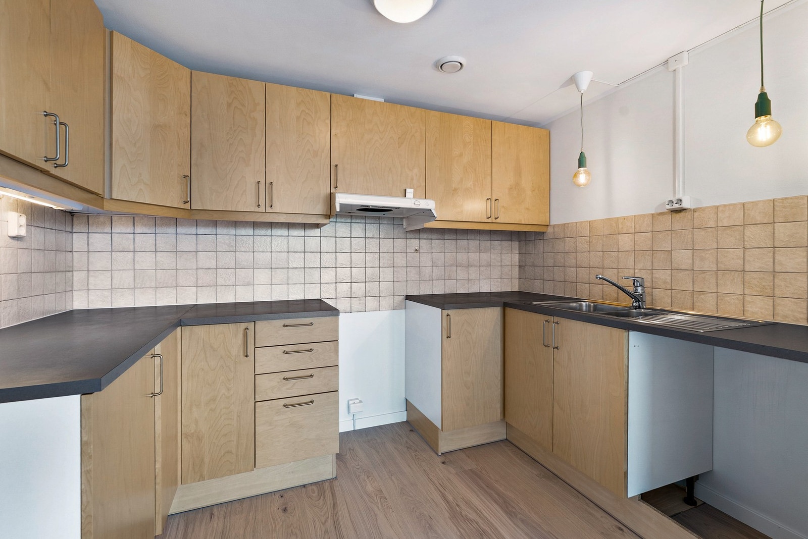 Kjøkkeninnredningen har slette fronter i treutførelse og en slitesterk laminatbenkeplate. Galleribilde