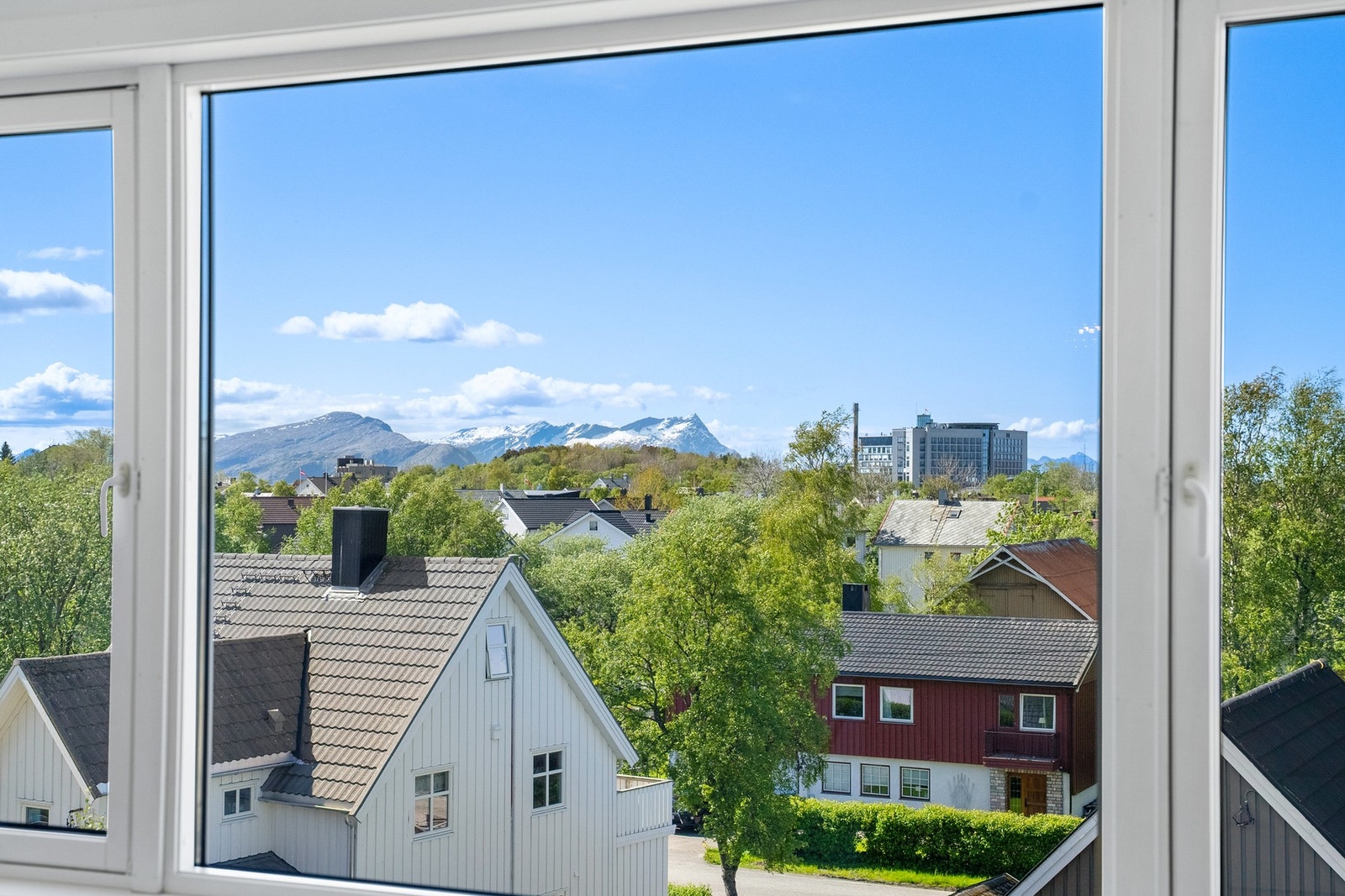 Gjennom stuevinduet ser man mot fjellene og deler av byen. Galleribilde
