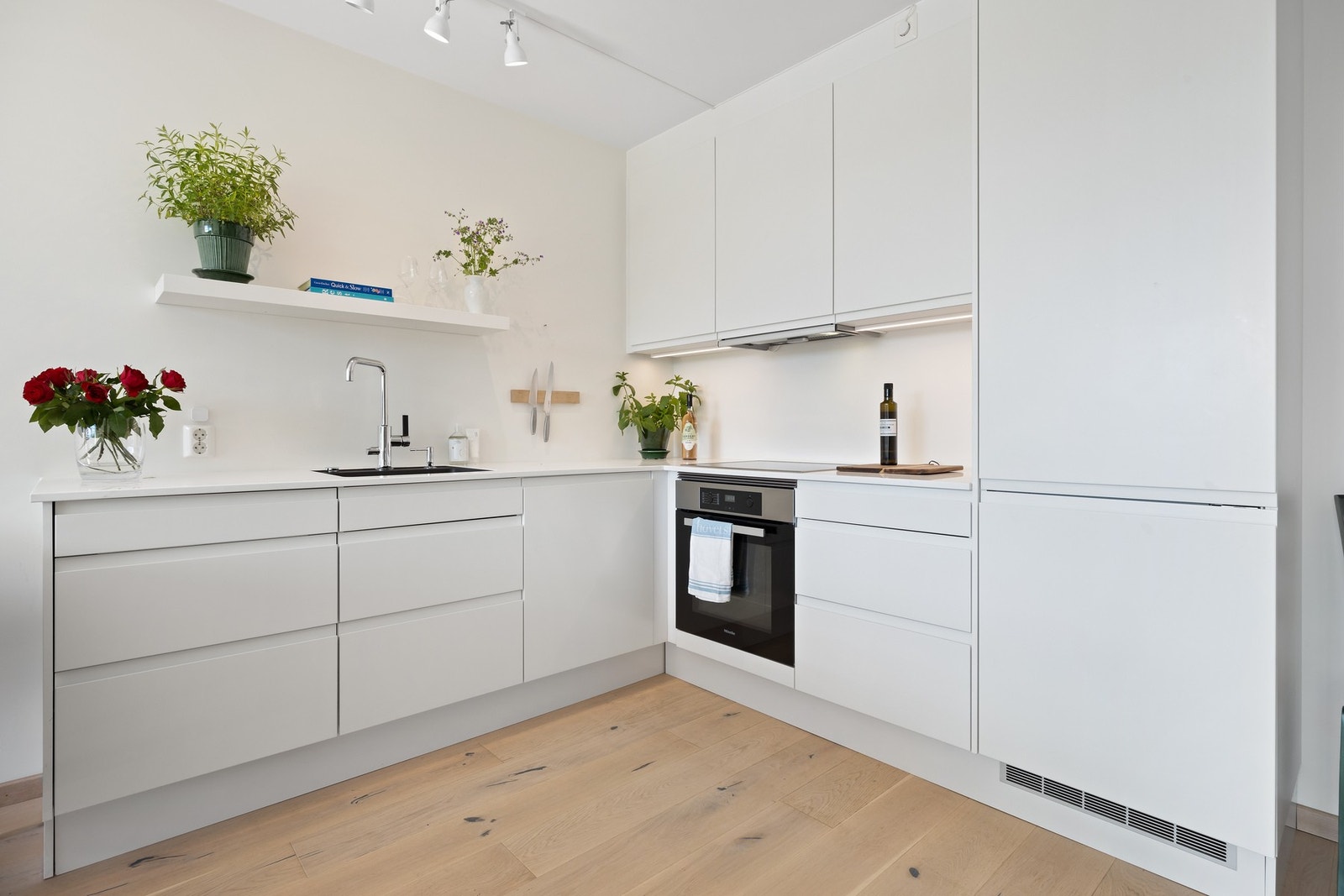 Moderne, lys kjøkkeninnredning med slette fronter og integrerte hvitevarer. Galleribilde
