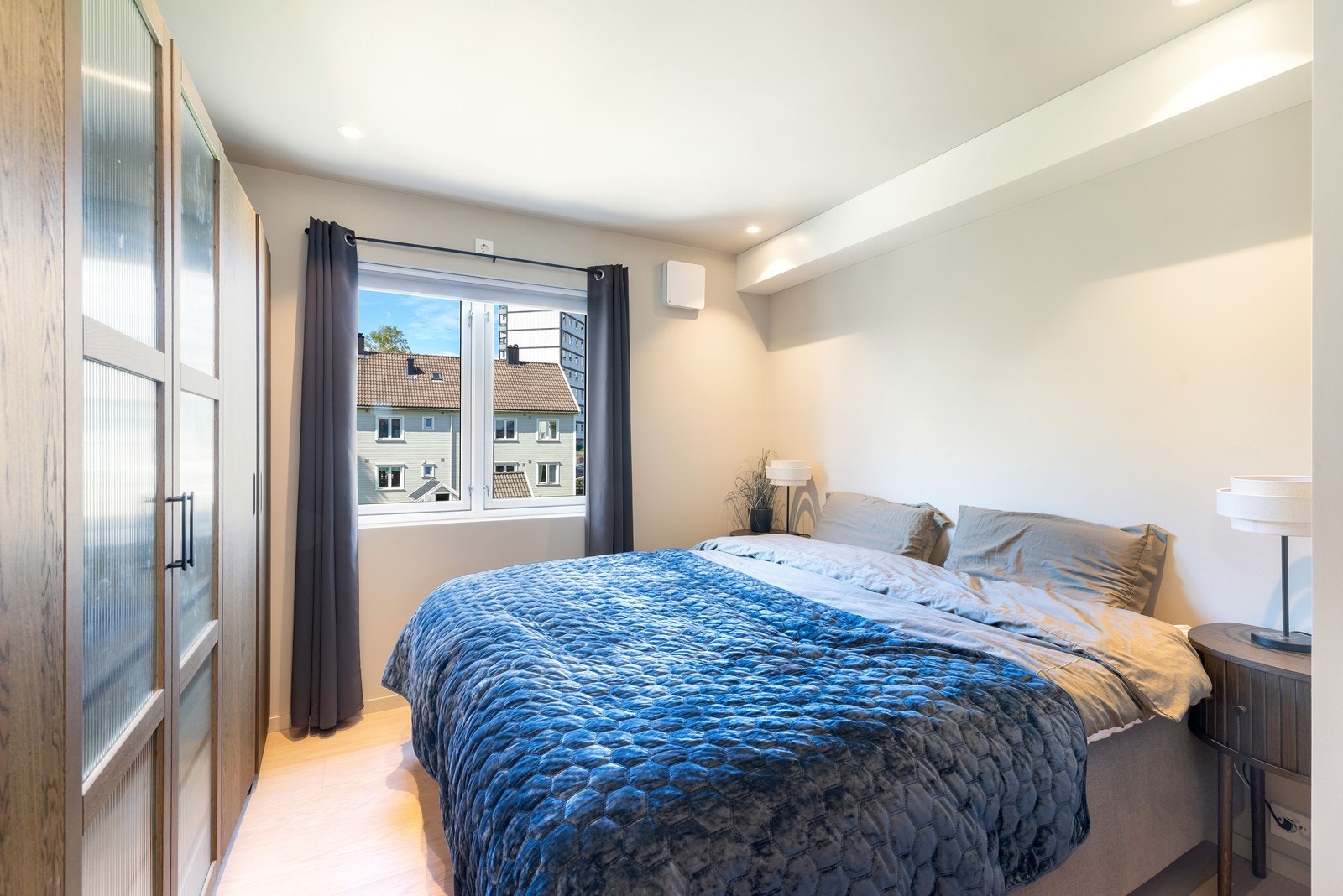 Plass til dobbeltseng og oppbevaring i et lyst hovedsoverom. Galleribilde