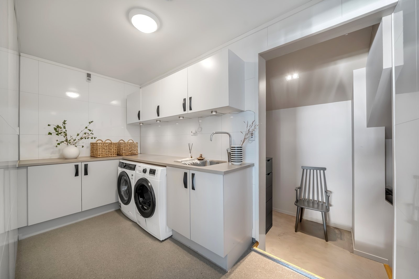 Praktisk vaskerom med baderomsplater på veggene, vinylbelegg med varmekabler og opplegg for vaskemaskin. Galleribilde