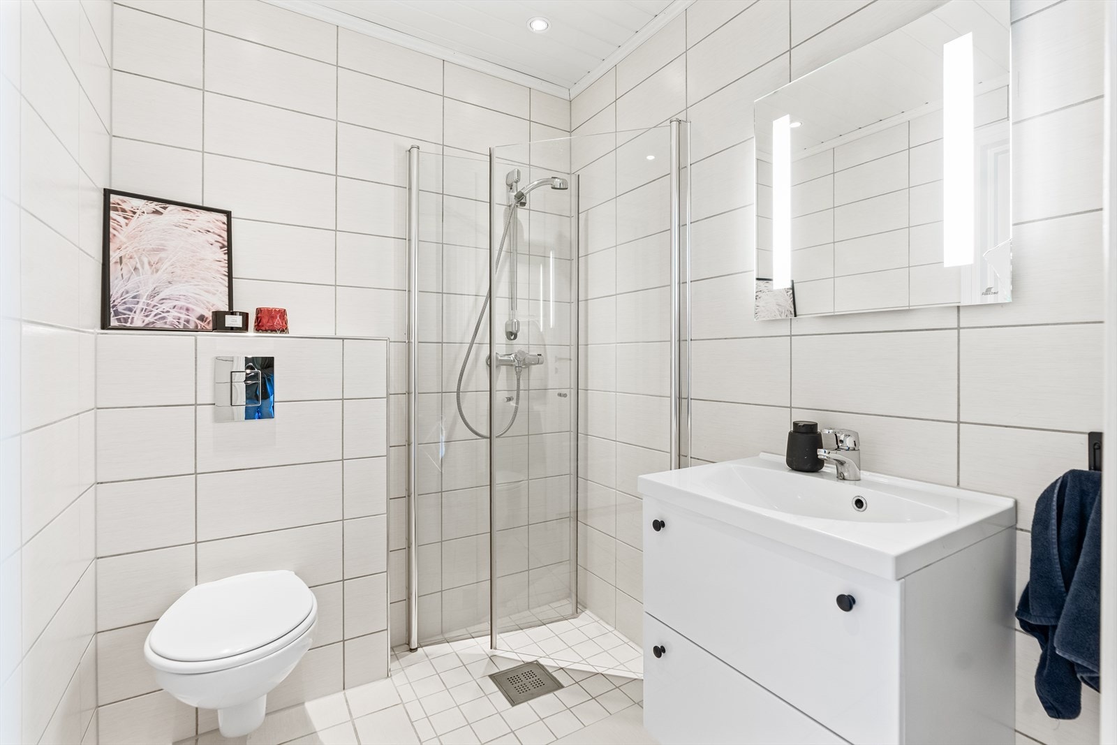 Badet i første etasje ligger i praktisk tilknytning til entreen, og har downlights i himlingen, hvite fliser på veggene og matchende gulvfliser med vannbåren gulvvarme. Galleribilde