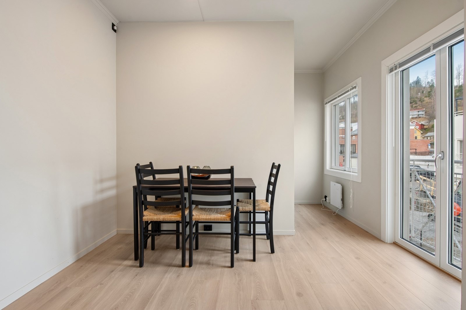 Stue og kjøkken ligger i åpen løsning. Et lyst og innbydende rom med store vindusflater som gir rikelig med naturlig lys. Sammen med enstavs laminat på gulv og lysmalte, slette flater fremstår oppholdsrommet som lyst og moderne. Galleribilde