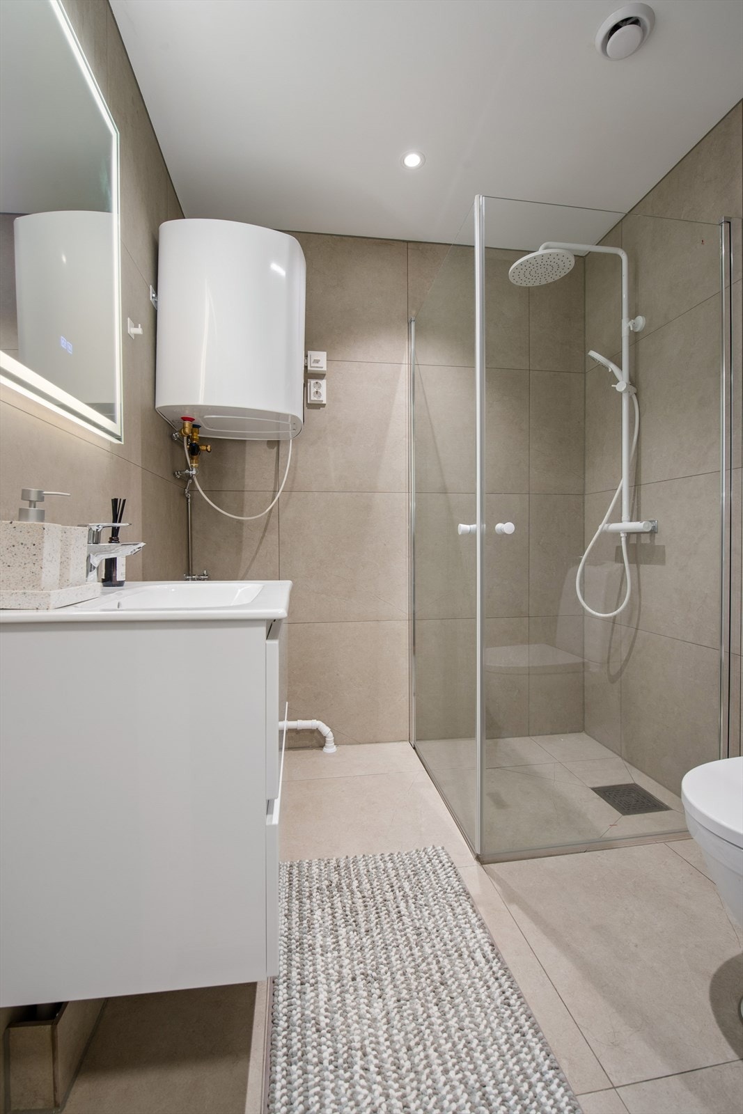 Badet ble renovert i 2025 og er delikat innredet med store, beige fliser på gulv og vegger. I gulvet har man også varme for ekstra komfort. Galleribilde