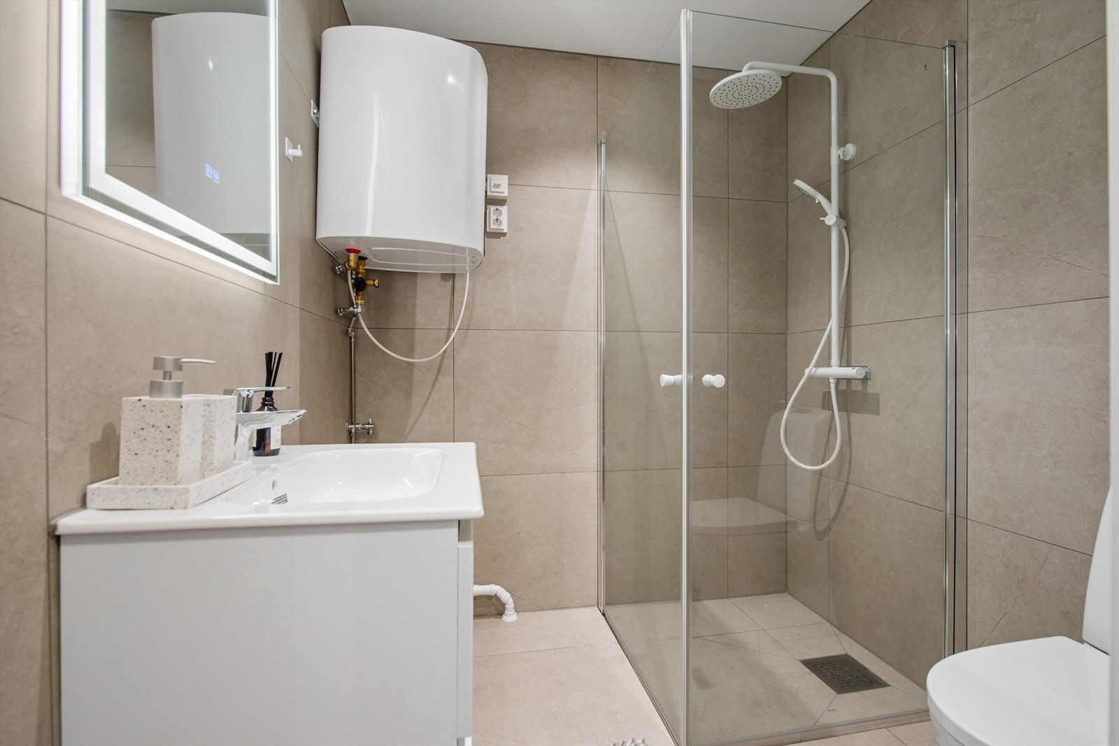 Badet er ellers utstyrt med dusjhjørne, toalett og baderomsinnredning med nedfelt servant. I tillegg har man opplegg for vaskemaskin. Avtrekk via mekanisk vifte og tilluft ved dør. Galleribilde