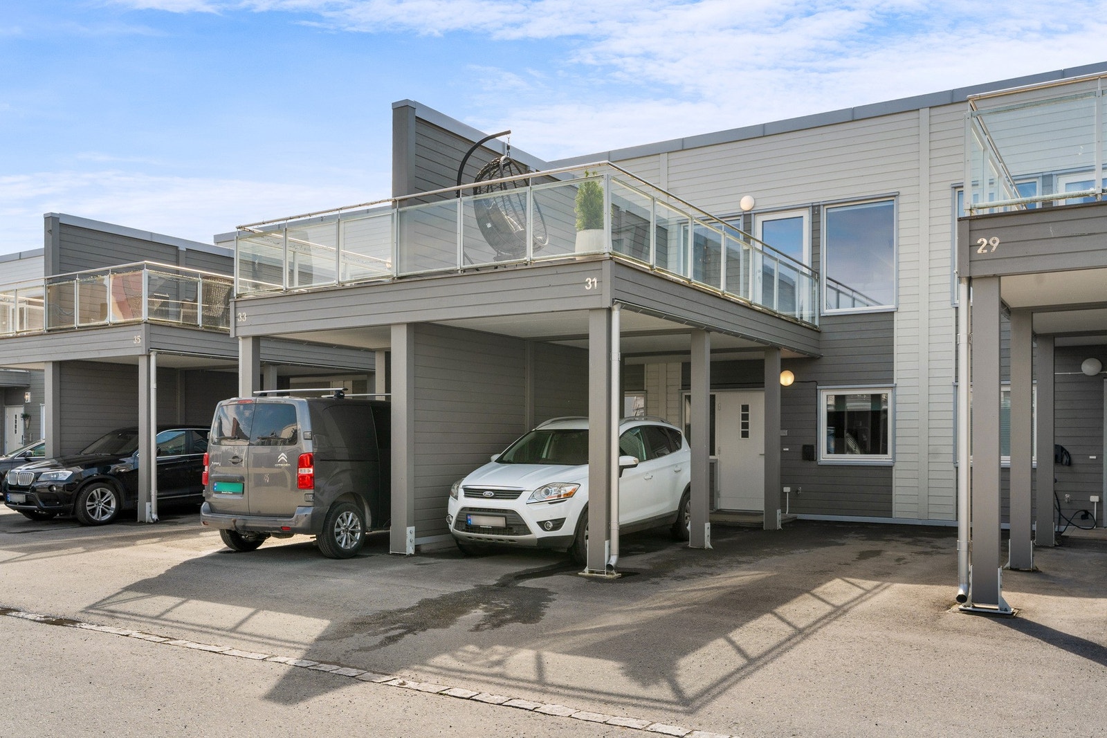 Carport rett utenfor inngangsdøra gjør at man kan gå tørrskodd inn i gangen. Her er det montert el-bil lader. Galleribilde