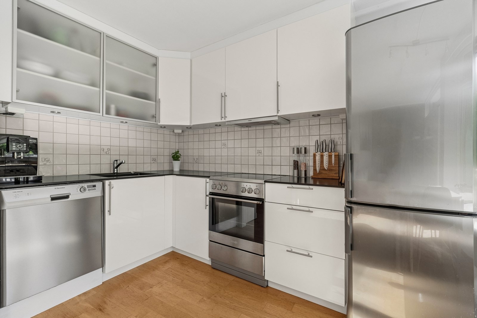 Innredningen har folierte fronter, to overskapdører med frostet glass, benkeplate i komposittmateriale og fliser over benken. Galleribilde