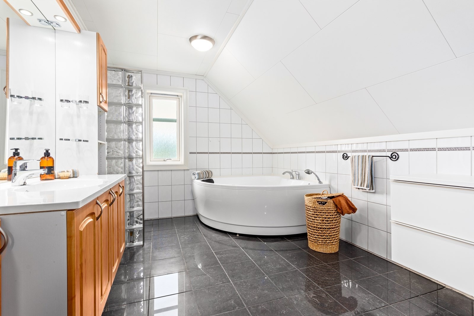 Bad på loft er innreia med servant med underskåp, vegghengt toalett, hjørnebadekar, og dusjveggar/hjørne med glasbyggarstein. Galleribilde