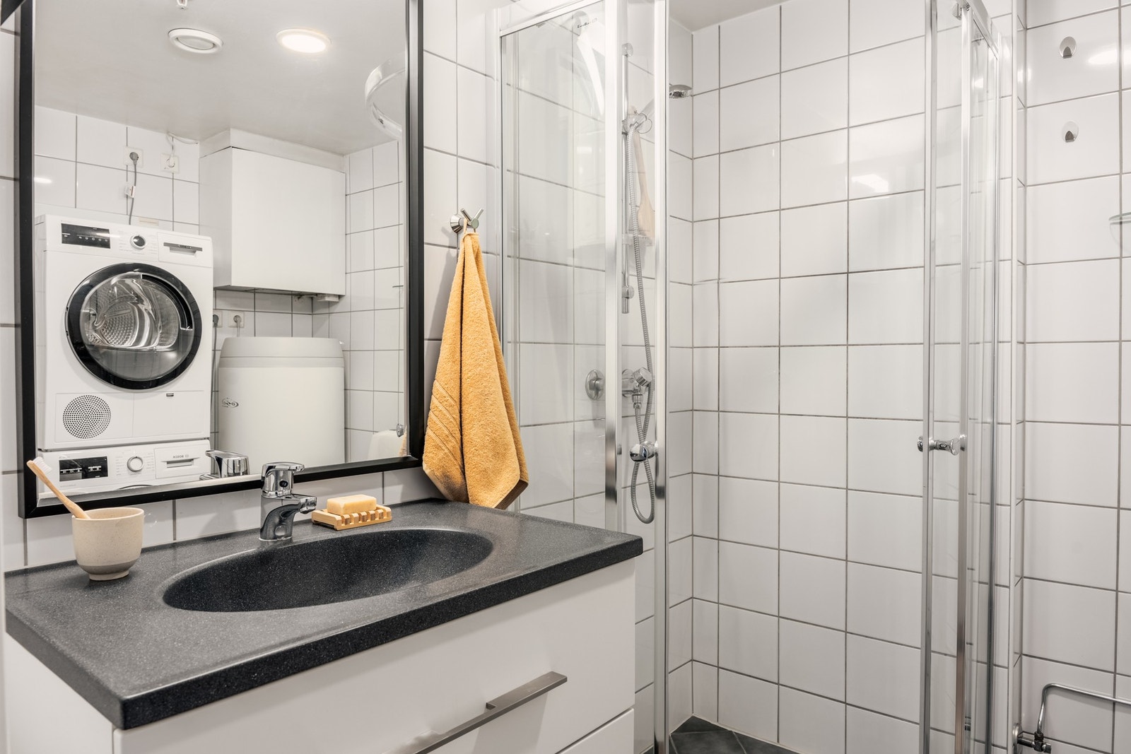 Badet er innredet med toalett, servant med innredning, dusjhjørne og opplegg for vaskemaskin. Galleribilde