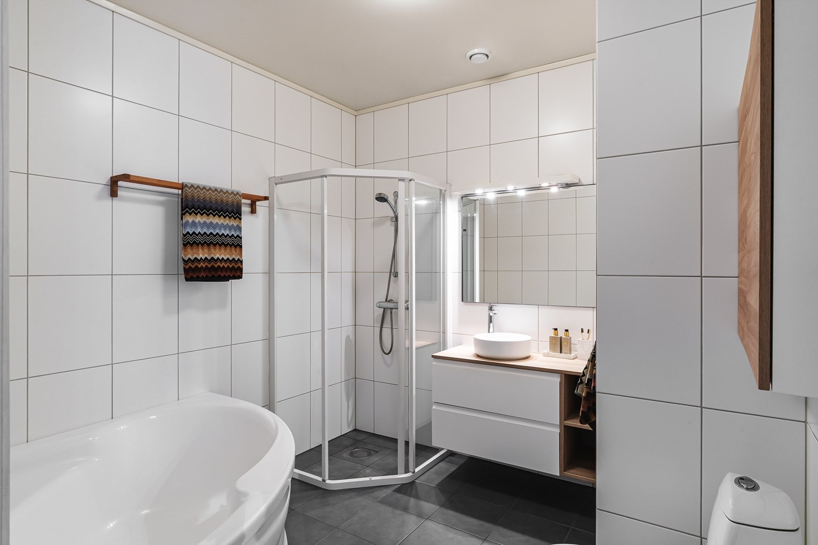Badet underetasjen med flislagte overflater, badekar og dusjhjørne. Galleribilde