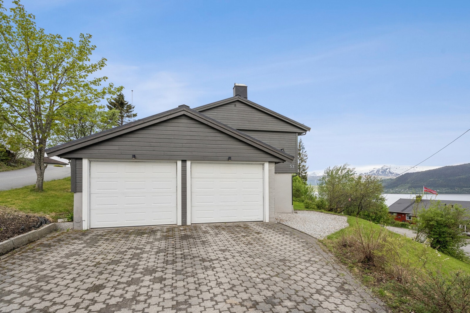 Integrert dobbelgarasje på 35 m² med leddporter med portåpner og belegningsstein i innkjørselen. Galleribilde