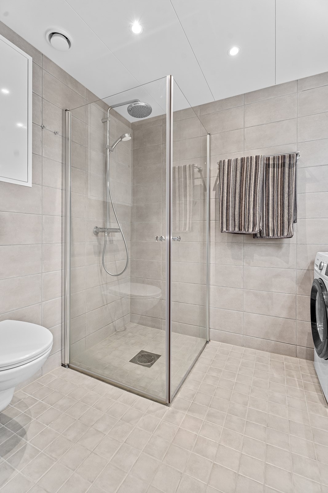 Badet er utstyrt med servant, servantskap, veggmontert wc, innfellbare dusjdører og opplegg for vaskemaskin. Galleribilde