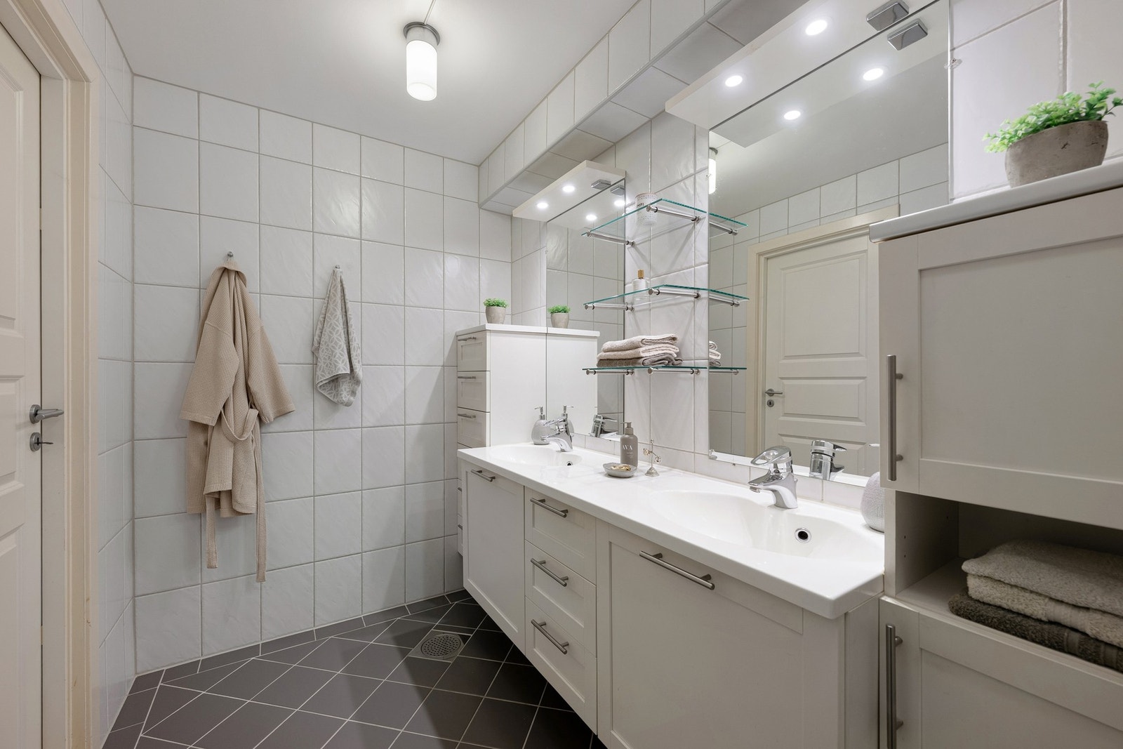 Badet har en romslig innredning med god benkeplass, oppbevaring og gulvvarme, samt mekanisk avtrekk og tidløse flislagte overflater. Galleribilde
