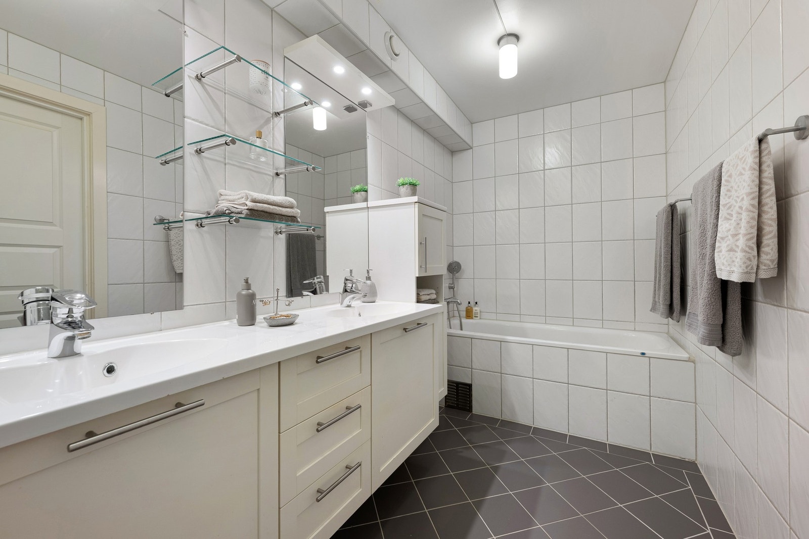 Flislagt bad ved soverommet, innredet med dobbel servant, speil med belysning og innfliset badekar. Badet ble pusset opp i 2005. Galleribilde