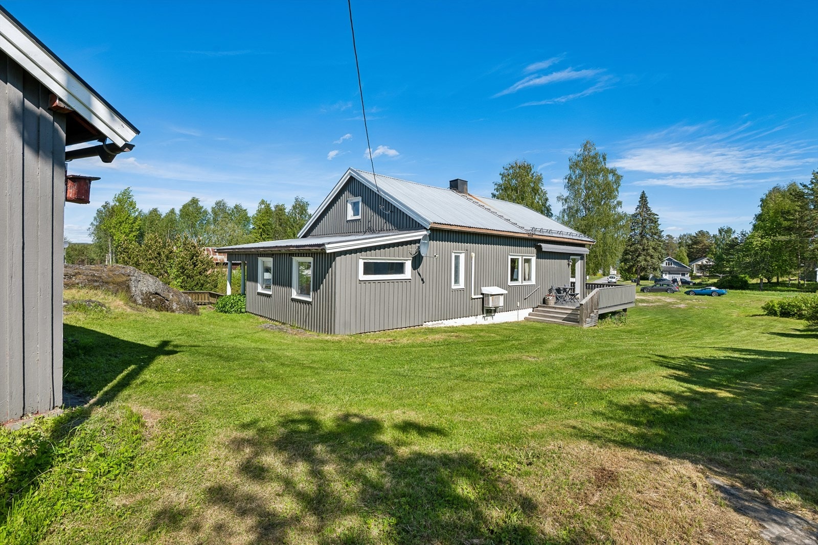 Eiendommen ligger i et skrånende terreng med opparbeidede plenarealer og gruset gårdsplass. Galleribilde