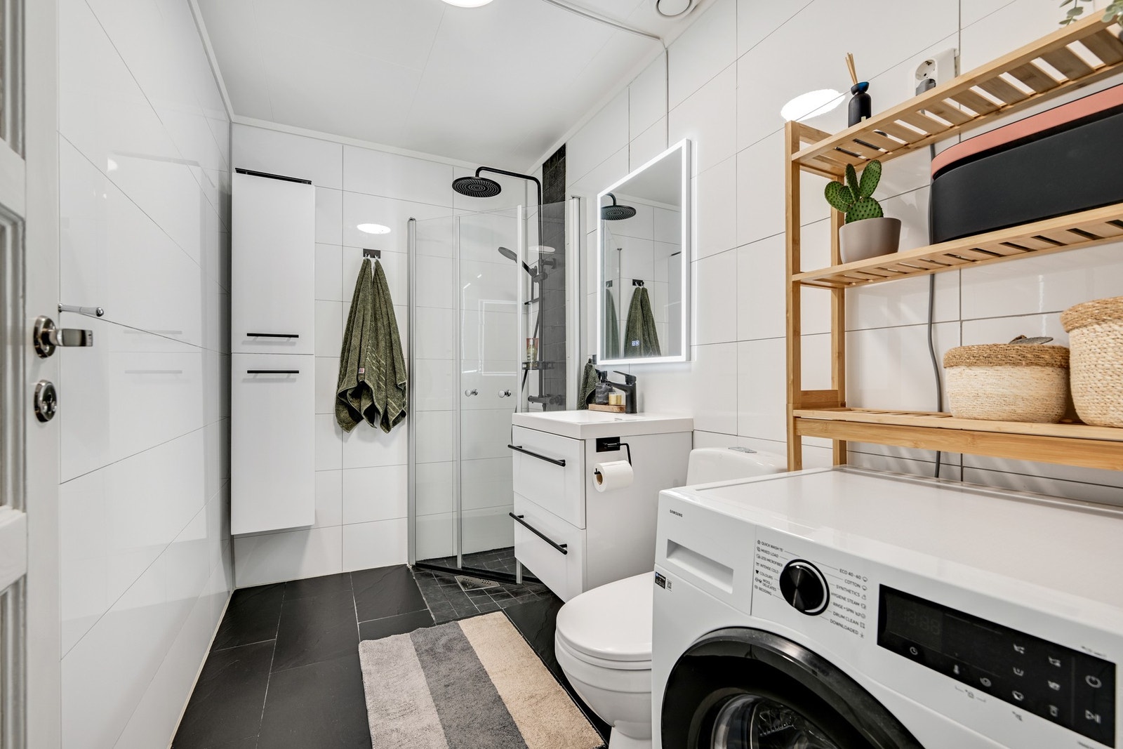 Størrelsen på badet er godt utnyttet og byr på et dusjhjørne, en servant med underskuffer og et klosett. Det er god plass til vaskemaskin og en tørketrommel over Galleribilde