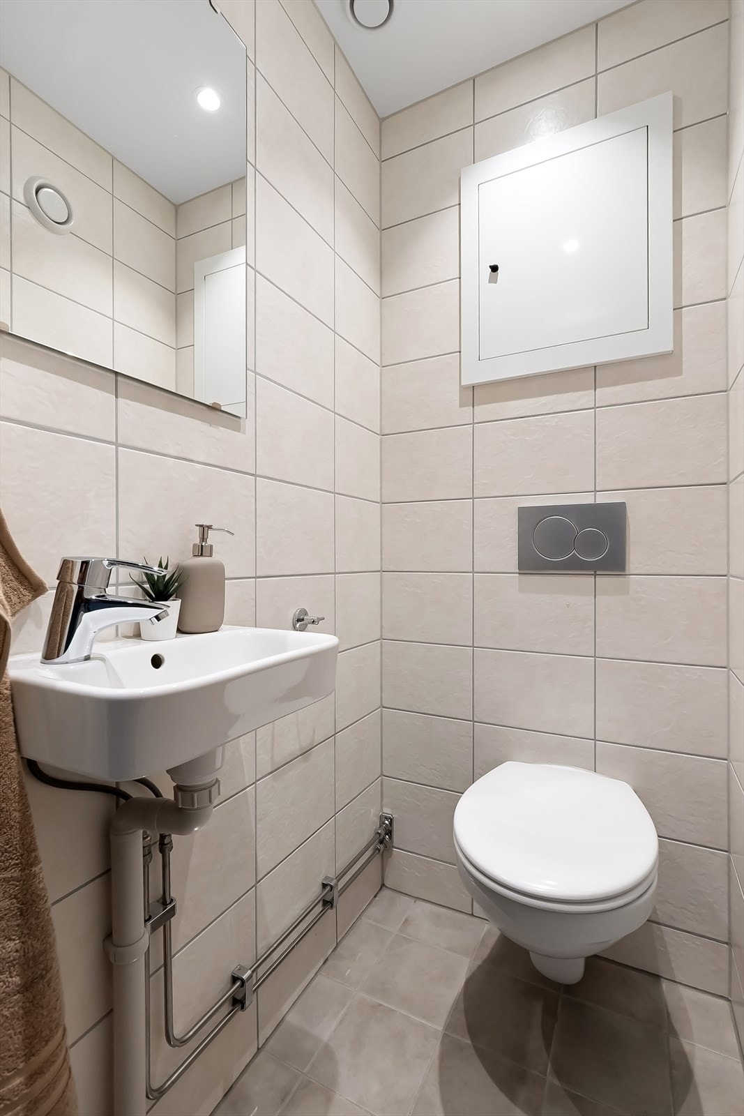 Separat toalettrom med flislagte overflater. Installasjoner med vegghengt toalett og servant med speil over. Galleribilde
