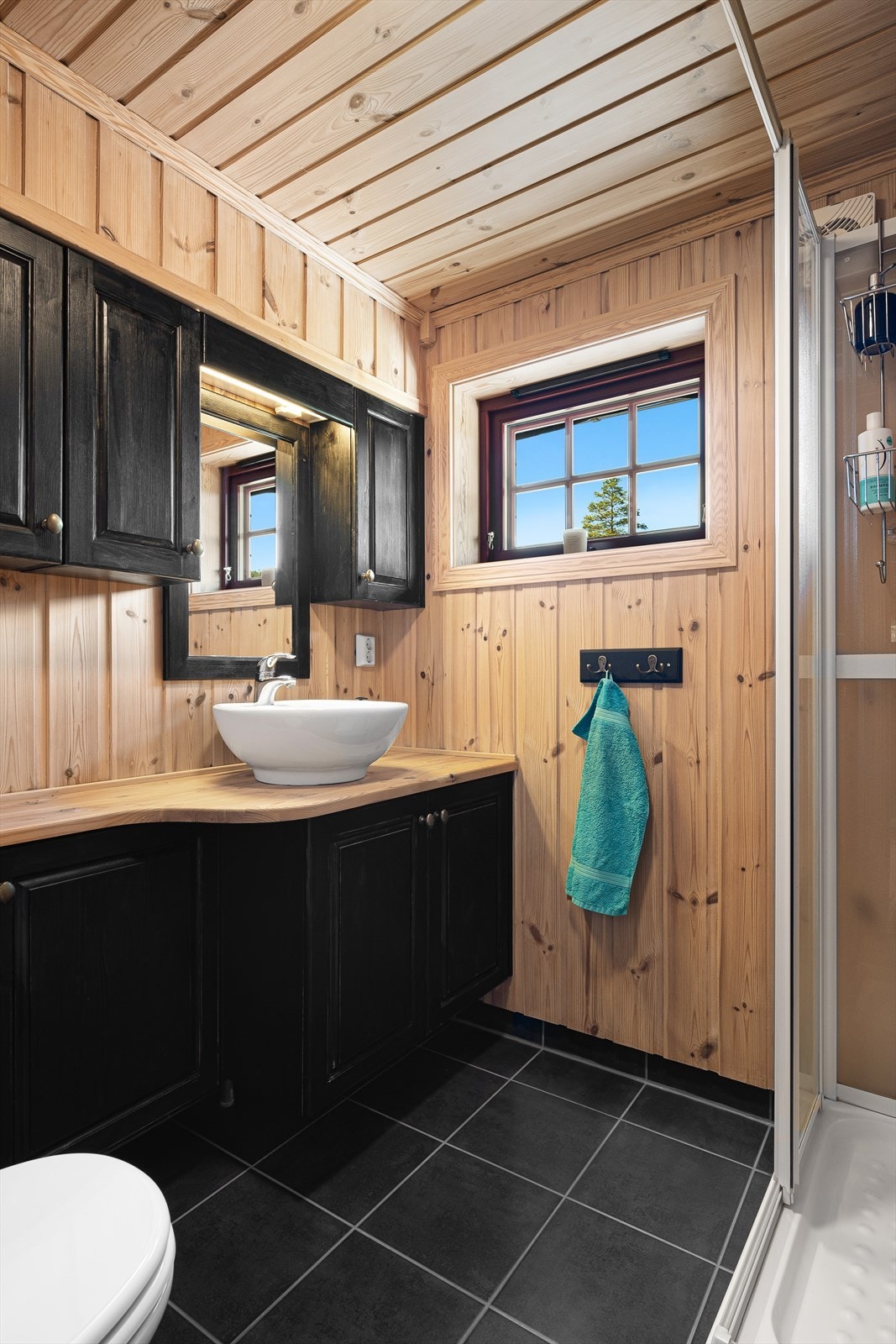 Badet har flislagt gulv med varmekabler på gulv, og furupanel på vegg. Galleribilde