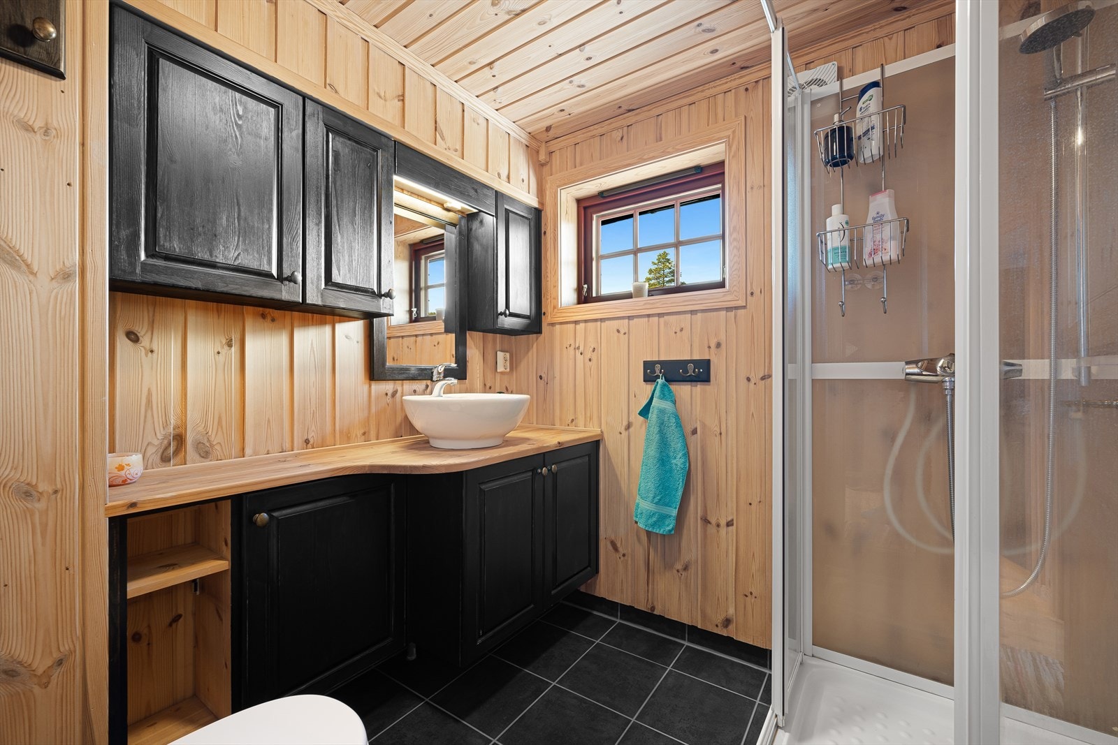 Badet inneholder servant med skap, dusjkabinett og snurredo. Galleribilde