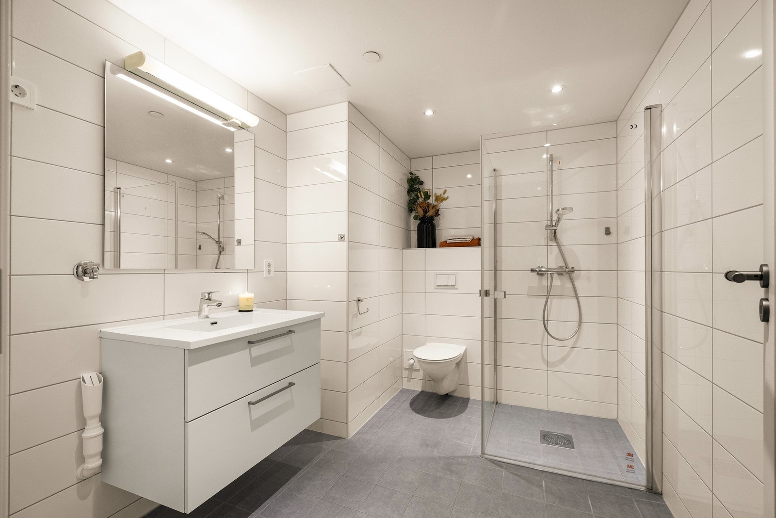 Badet har et tidløst uttrykk med lyse overflater og en praktisk planløsning med opplegg for vaskemaskin. Galleribilde