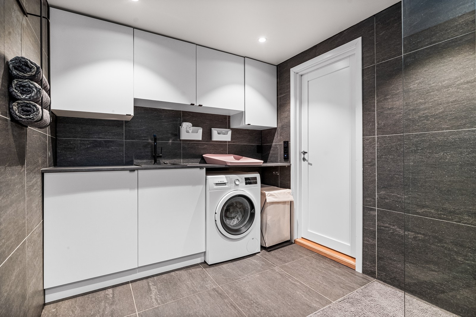 Egen vaskeromsdel på badet med benkeplate, utslagskum og opplegg for vaskemaskin. Galleribilde