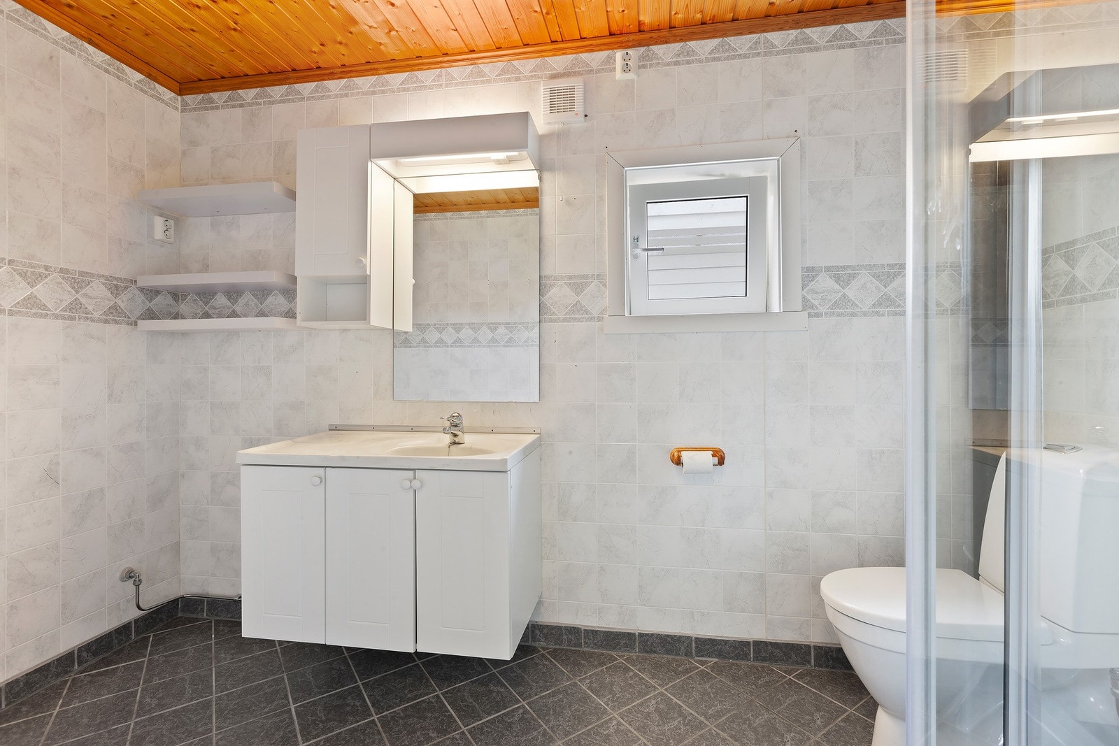 Badet har innredning med nedfelt servant og skap under, overskap og speil med lys over, dusjkabinett og toalett. Varme i gulv. Galleribilde