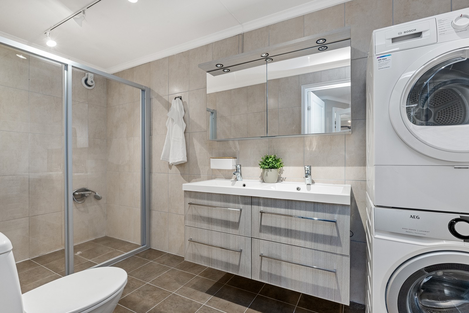 Badet er kombinert vaskerom med opplegg for vaskemaskin og tørketrommel. Galleribilde