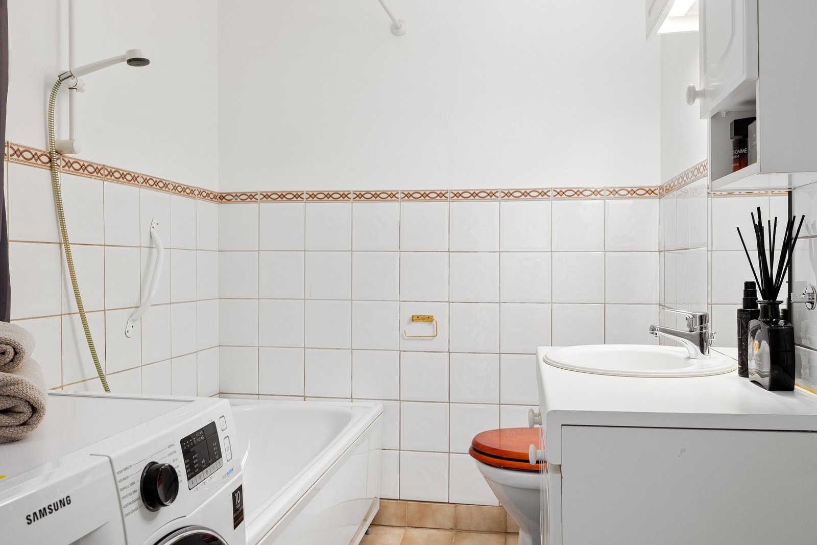 Eldre bad med badekar, toalett, servant med skap, vegghengt skap og speil med lys Galleribilde