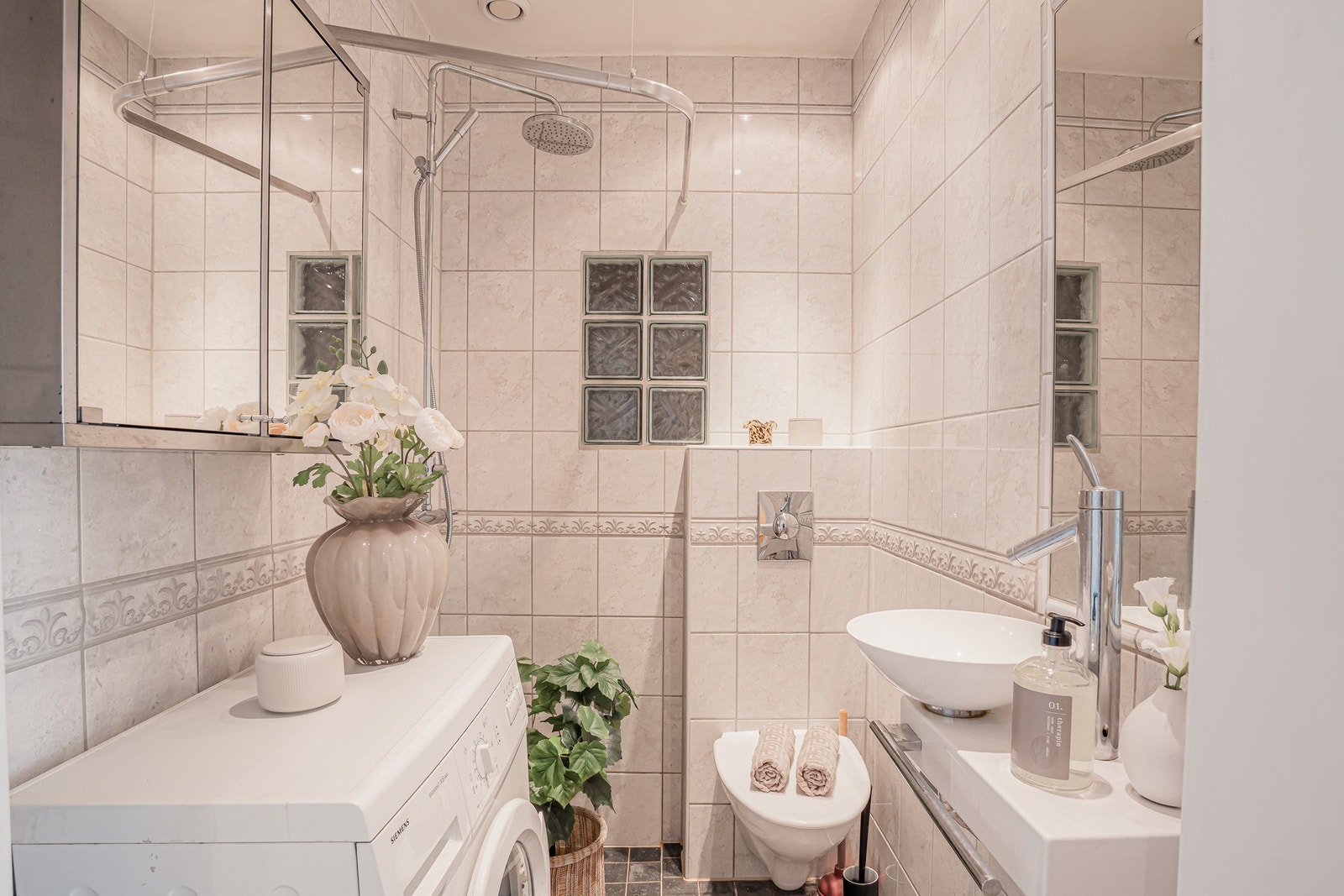 Flislagt baderom med varmekabler i gulv. Badet er innredet med servant med tilhørende blandebatteri, dusjhjørne med forheng, vegghengt toalett samt overskap med speilfronter. Galleribilde