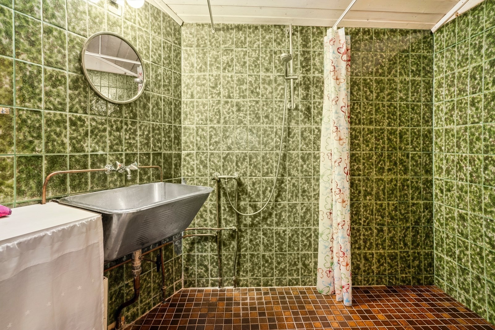 Badet har grønne fliser på vegg og brune på gulvet. Galleribilde
