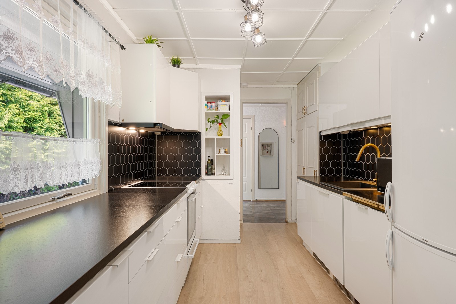 Kjøkkeninnredningen er tidløs, med hvite, glatte fronter, nedfelt oppvaskkum og laminert benkeplate i sort utførelse. En oppvaskmaskin er integrert i innredningen. Galleribilde