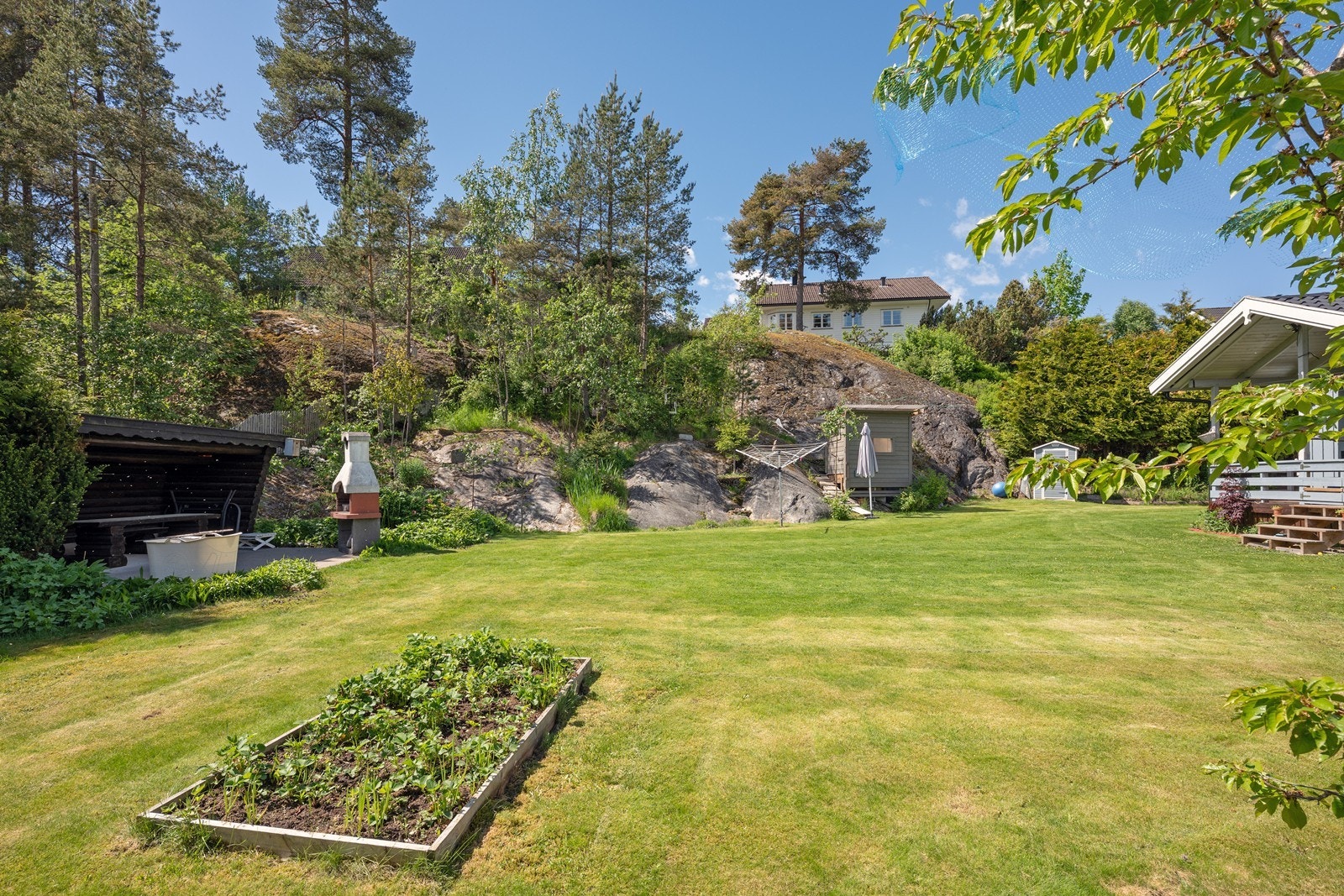 Tomten er opparbeidet med hekker, store plenarealer og diverse beplantning - supplert av fjell i dagen og stedlig vegetasjon. Galleribilde