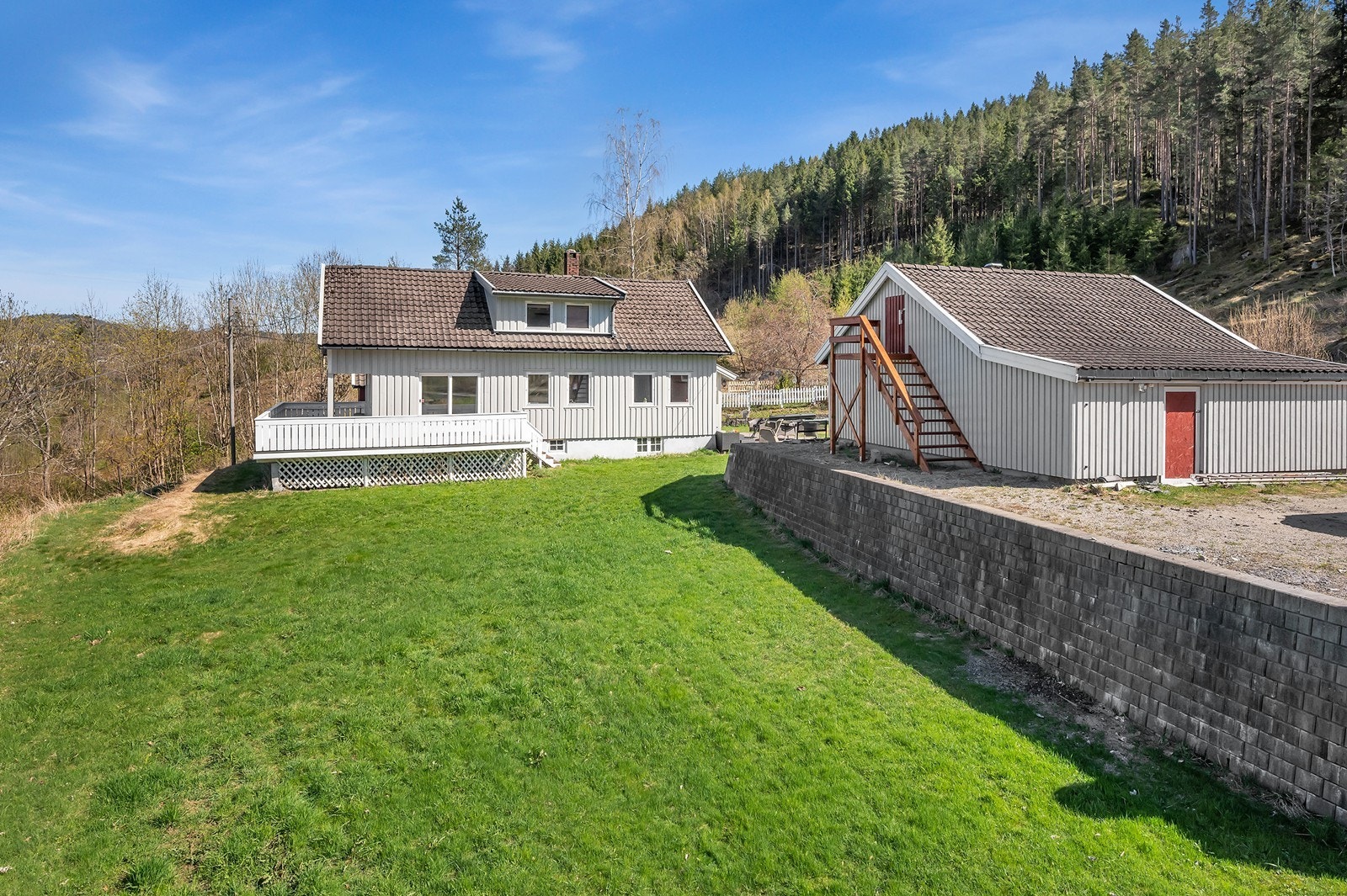 Eiendommen har et romslig uteområde med plen og frittliggende bygninger. Galleribilde