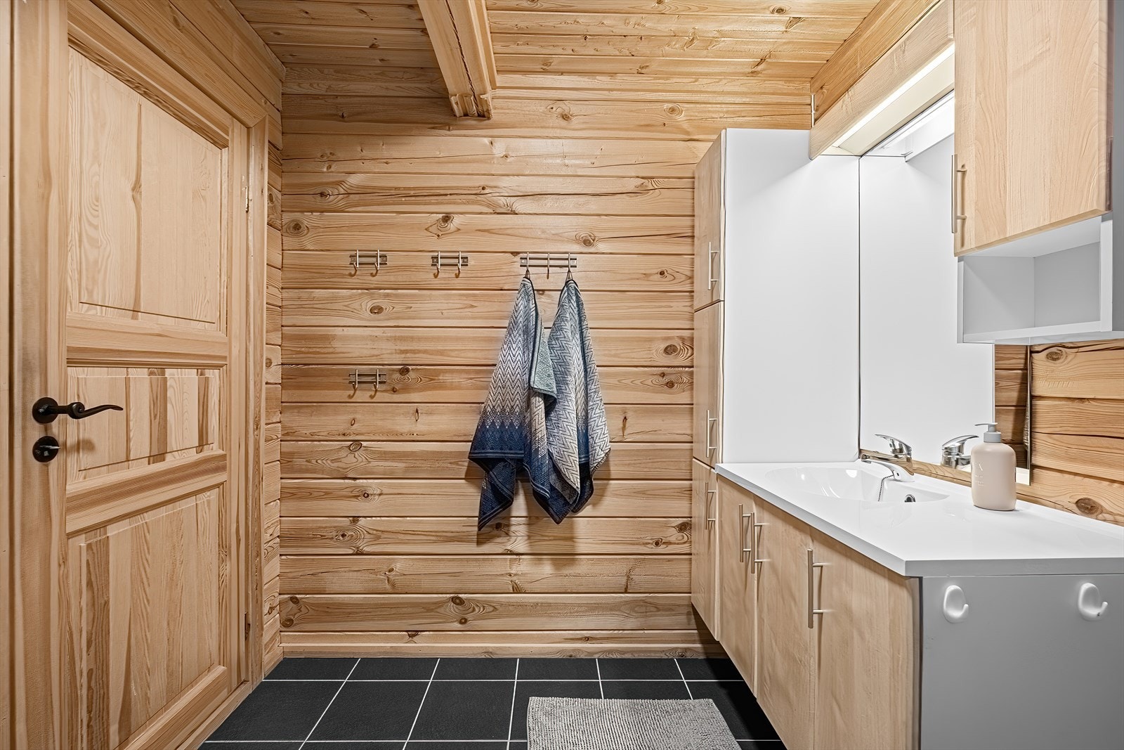 Badet har furupanel på vegg og flislagt gulv med varmekabler. Galleribilde