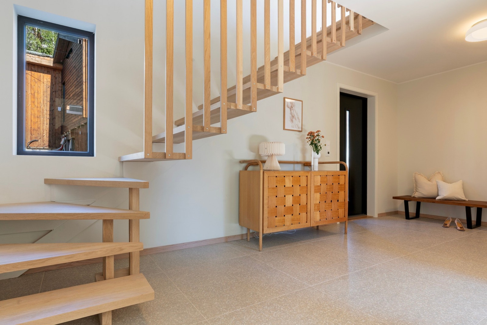 Velkommen inn | Romslig hall på 15 m² med gulv som er lagt med fliser i 80 x 80 | Stilren designtrapp med åpne trinn og spiler Galleribilde