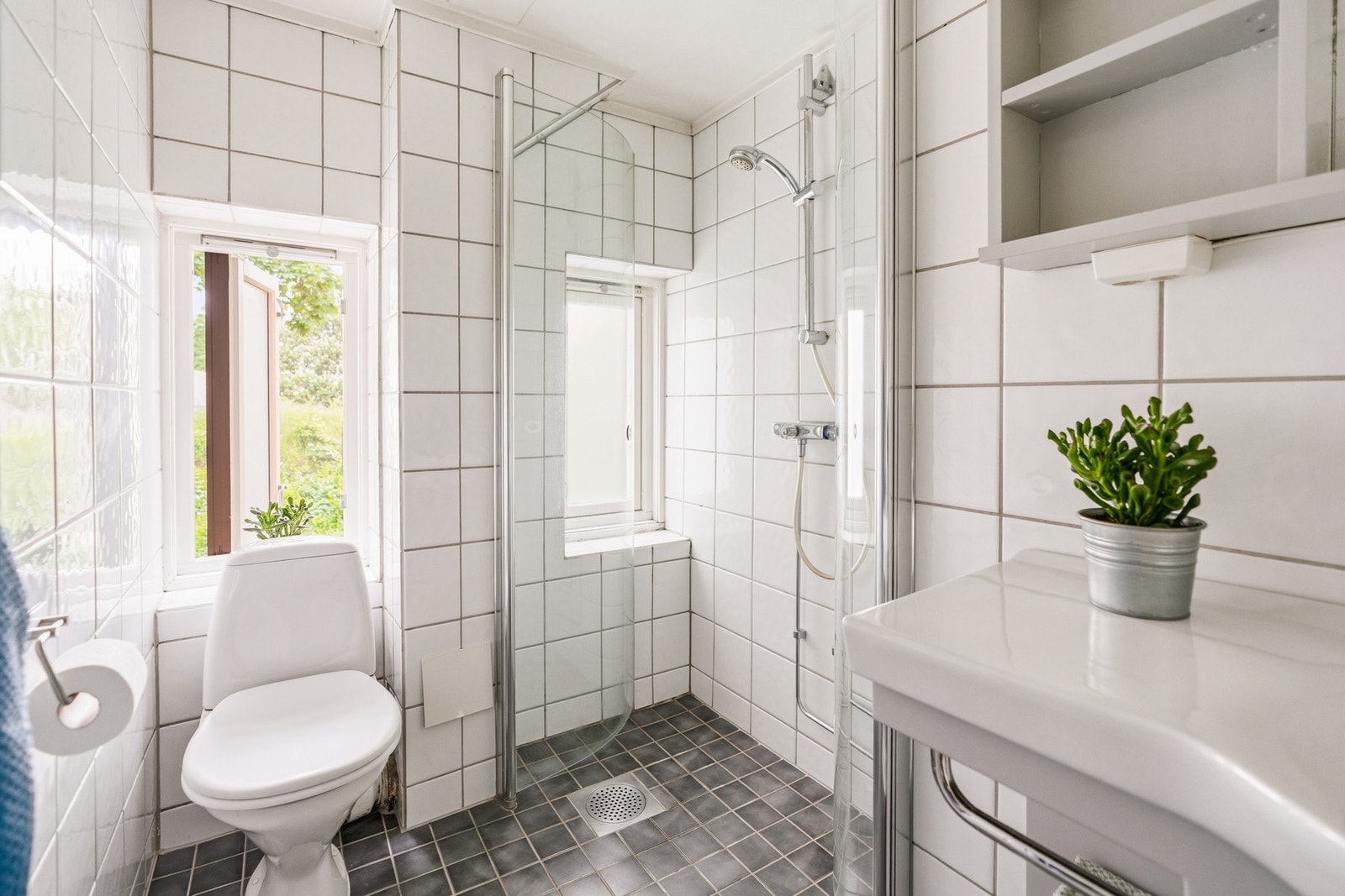Badet er innredet med servant, toalett og dusjsone. Badet har tilluft via luftespalte under dør og naturlig utluftning gjennom to vinduer. Galleribilde