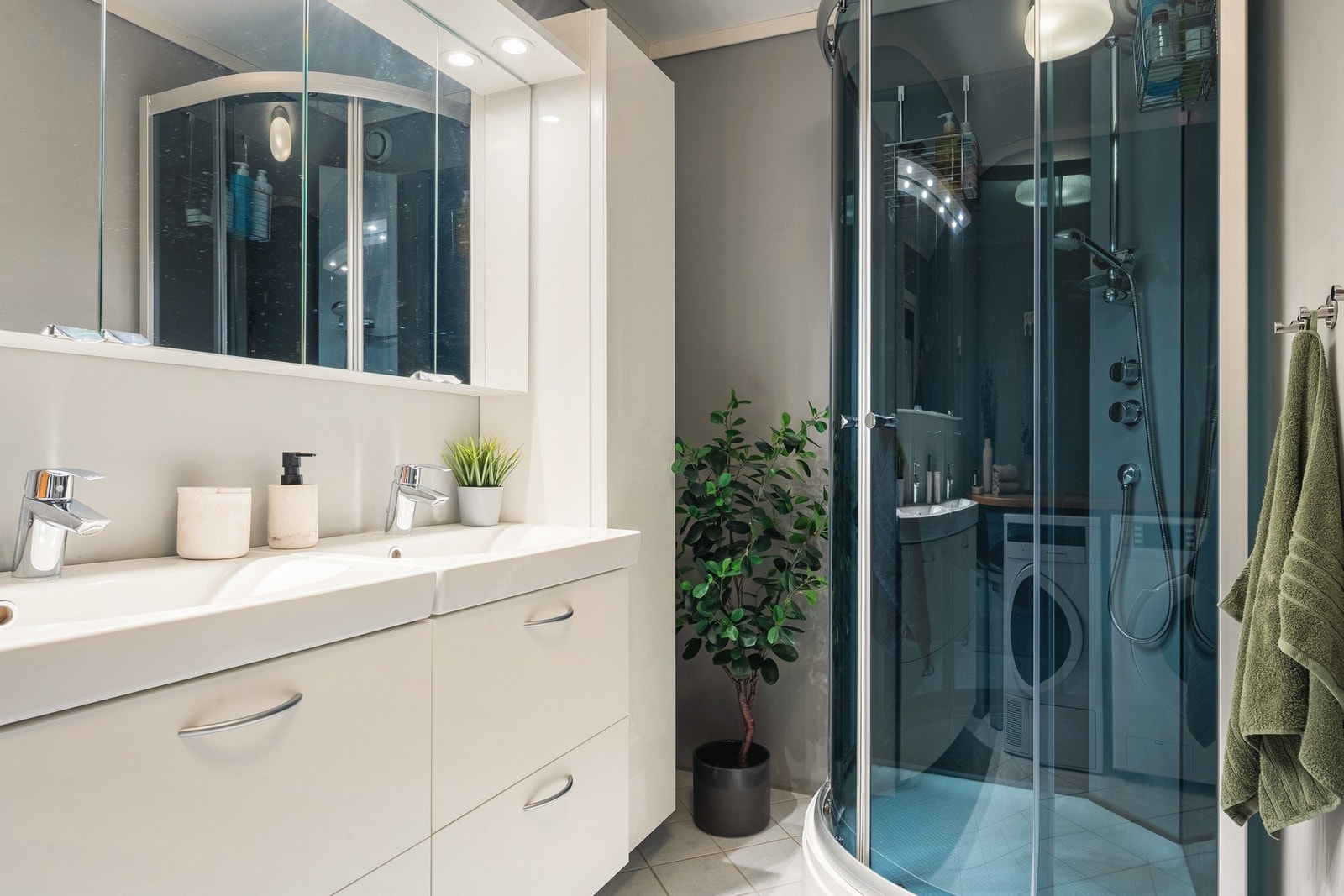 Badet er innredet med servant med møblement/speil, belysning, dusjkabinett, benkeplate med utslagsvask og opplegg for vaskemaskin. Galleribilde