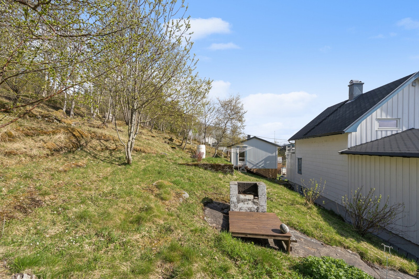 Tomten er opparbeidet med plen og har delvis naturtomtpreg, plassert i et skrånende terreng. Galleribilde
