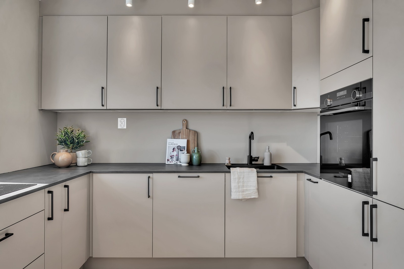 Moderne kjøkkeninnredning med glatte fronter, benkeplate i laminat og underlimt oppvaskkum. Galleribilde