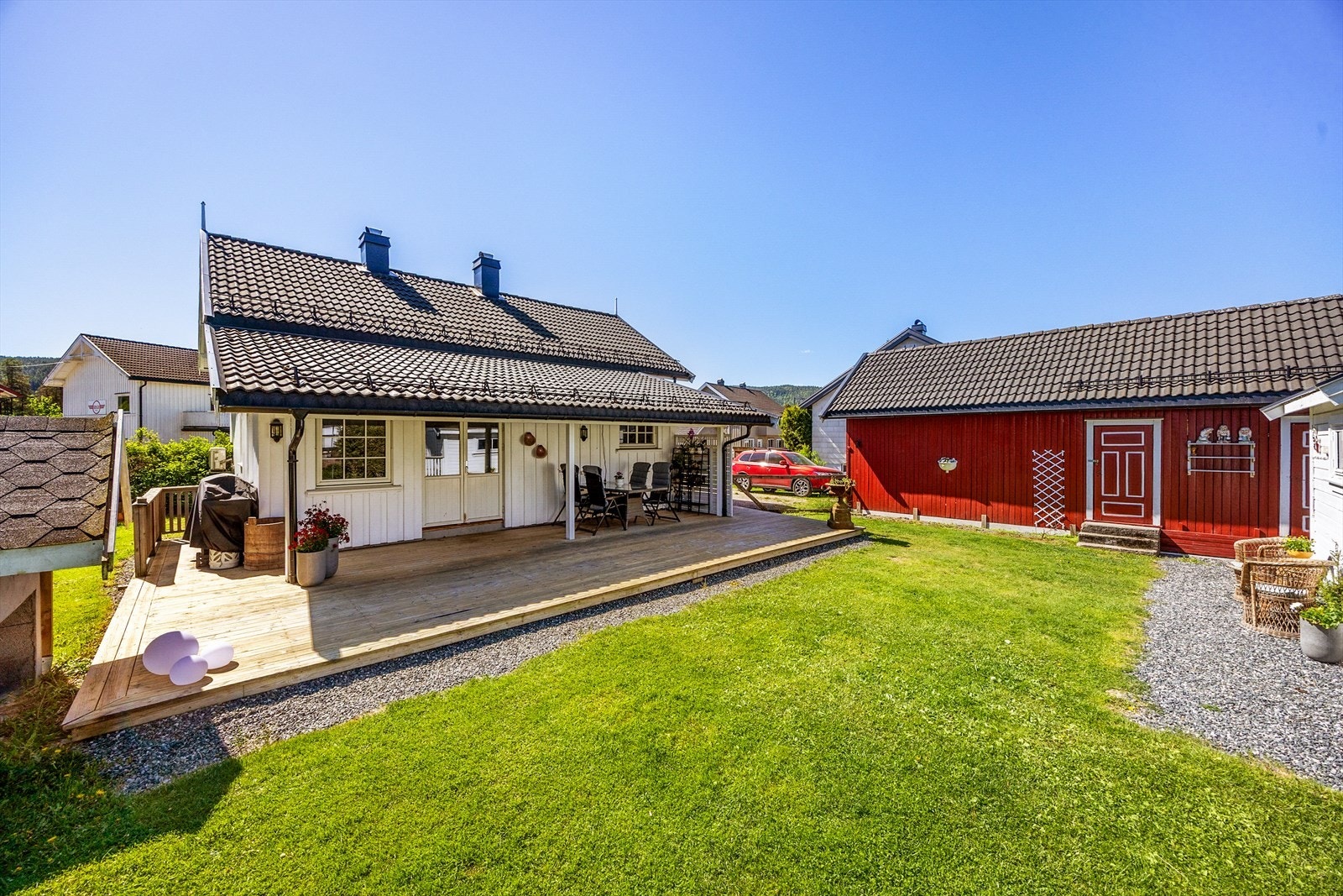 Tomten er pent opparbeidet med plen, beplantning og gruslagte stier. Galleribilde