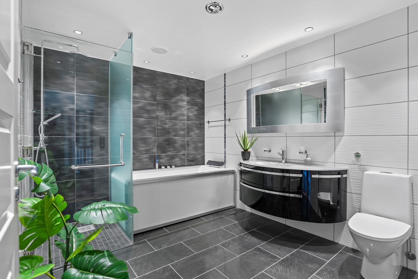 Badet er innredet med badekar med massasjefunksjon. I tillegg er det etablert en egen dusjnisje med glassvegg og glassdør, som gir et stilrent og moderne uttrykk. Galleribilde